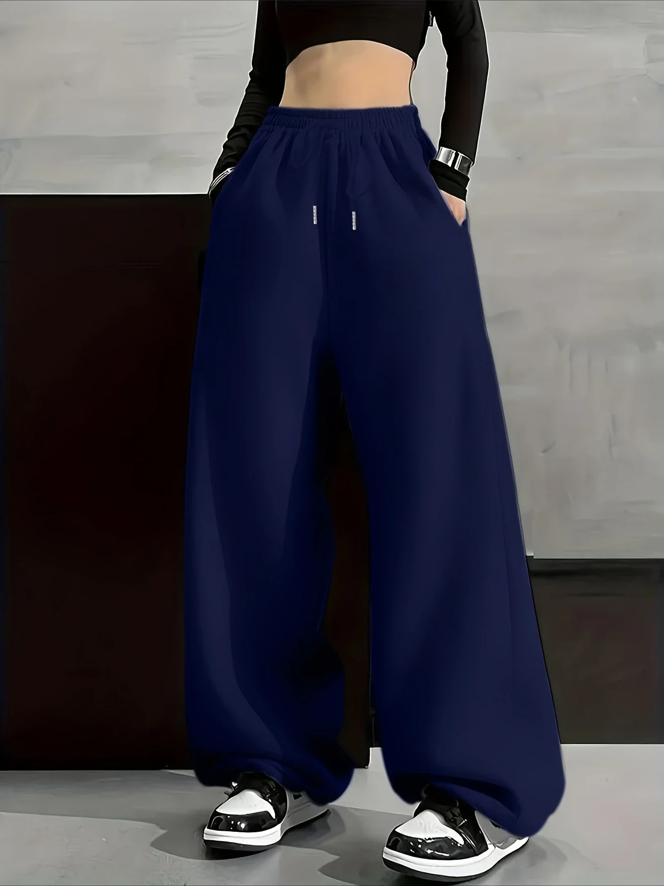 Model wearing navy wide-leg sweatpants with a black crop top